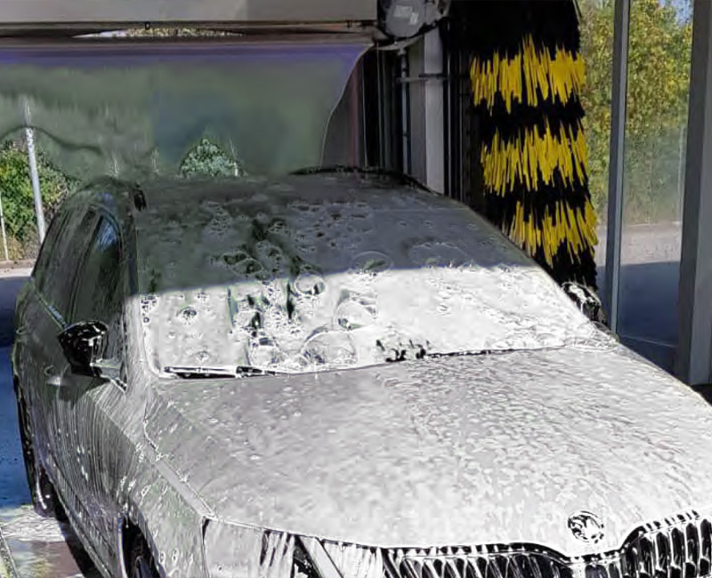 Operaio lavaggio auto con schiuma attiva su un autolavaggio.